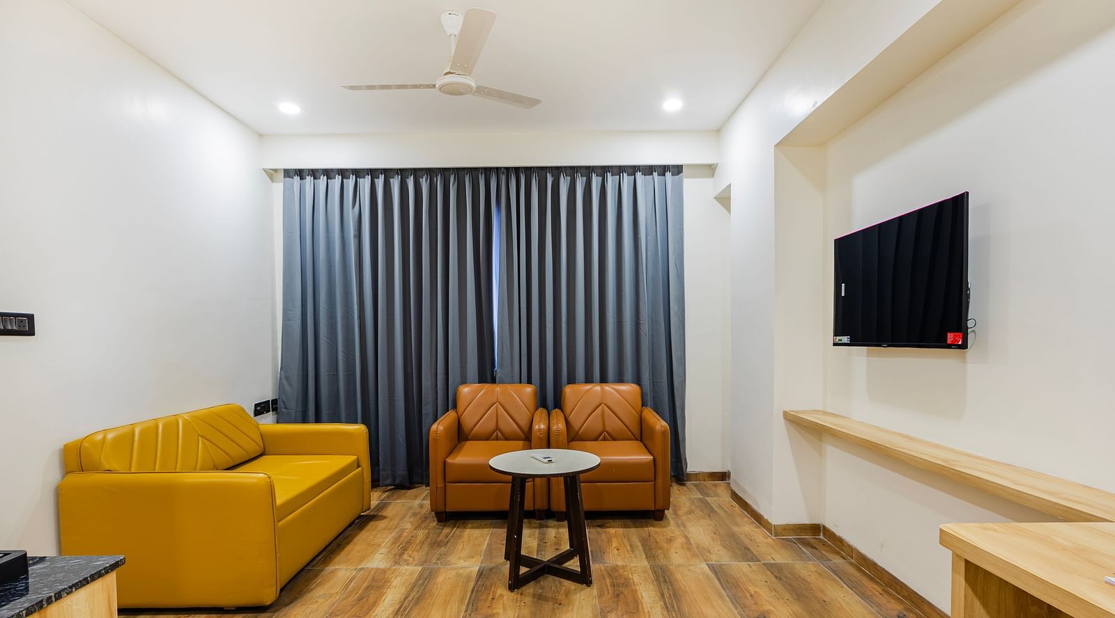 Lemonridge Hotels, KPHB | Hotel room with a sofa, two armchairs, and a coffee table.  TV on the wall. Comfortable seating area.